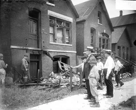 White men and boys standing in front of a vandalized house - Red Summer