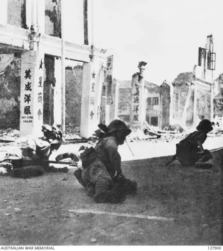 Troops of the Japanese Army crouch on a street in Johor Bahru